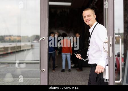 Porträt eines lächelnden jungen Geschäftsmanns, der vor der Tür des Convention Centers steht Stockfoto