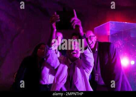 Fröhlicher Geschäftsmann, der Selfie mit Kollegen über Smartphone im Messezentrum macht Stockfoto