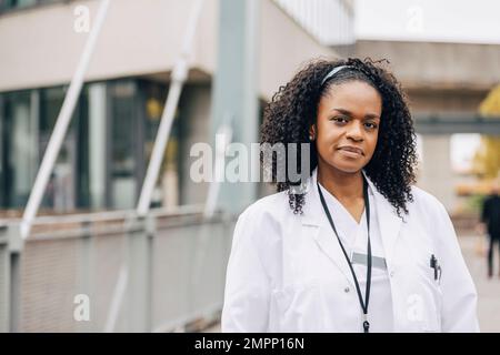 Porträt einer selbstbewussten Arztin im Laborkittel ausserhalb des Krankenhauses Stockfoto