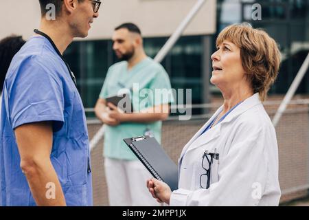 Seitenansicht eines männlichen Kollegen, der mit einer Arztin spricht Stockfoto