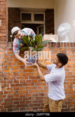 Seitenansicht eines Mannes, der über eine Backsteinwand an seinen Freund vorbeiläuft Stockfoto