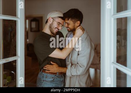 Ein liebenswertes schwules Paar, das zu Hause lächelt Stockfoto