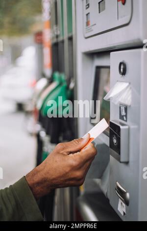 Mann mit Kreditkarte während der Bezahlung an der Tankstelle Stockfoto