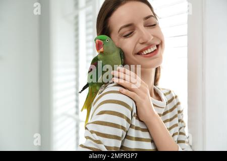 Junge Frau mit süßem Alexandrinen-Sittich drinnen Stockfoto