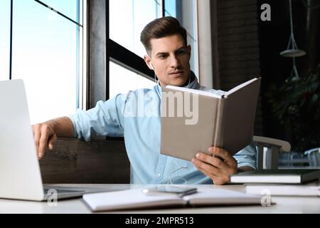 Ein Mann, der am Tisch im Café Hörbücher hört Stockfoto