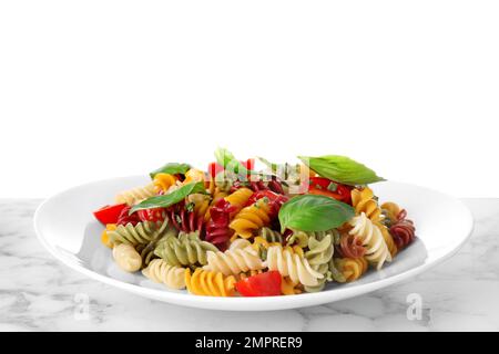 Bunte Pasta mit Basilikum und Kirschtomaten auf einem Marmortisch vor weißem Hintergrund Stockfoto