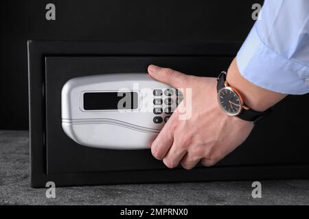 Mann öffnet schwarzen Stahlsafe mit elektronischem Schloss, Schließung Stockfoto