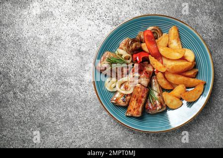 Köstliche gegrillte Rippchen und Garnierung auf grauem Tisch, Draufsicht. Platz für Text Stockfoto