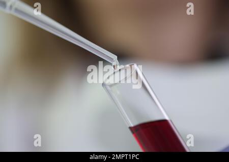 Labordiagnostiker tropft Flüssigkeit mit Blutverschlüssen in das Reagenzglas Stockfoto