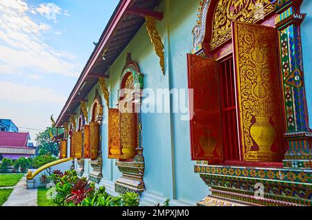 Fensterläden aus Holz und kunstvoll verzierte Fensterrahmen des Viharn im Wat Chiang man Tempel, Chiang Mai, Thailand Stockfoto