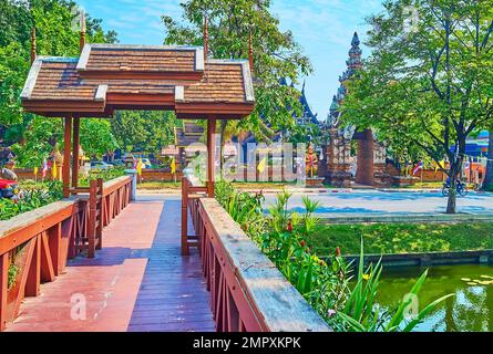 Dekoratives Tor auf einer Fußgängerbrücke über den Old City Moat mit Blick auf schattige Bäume und Wat Lok Moli im Hintergrund, Chiang Mai, Thailand Stockfoto