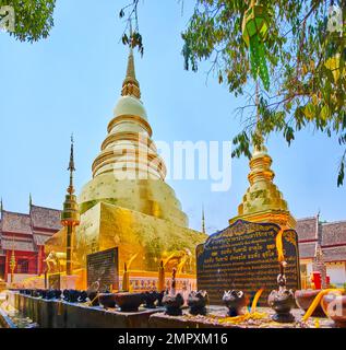 Der Altar mit brennenden Kerzen und Räucherstäbchen vor Phra, den Luang chedi (Stupa) des Wat Phra Singh Tempels, Chiang Mai, Thailand Stockfoto