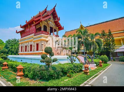 Der Topiargarten um das mittelalterliche Manuskriptlager von Wat Phra Singh, dekoriert mit Skulpturen von Devata-Gottheiten, Naga-Schlangen und Stockfoto