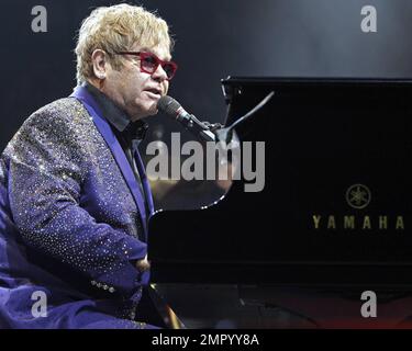 Elton John trägt eine rote gerahmte Brille und einen paillettenfarbenen Anzug mit der Aufschrift „Captain Fantastic“ auf der Rückseite, während er live im BankAtlantic Center in Sunrise, FL auftritt. 9. März 2012 Stockfoto