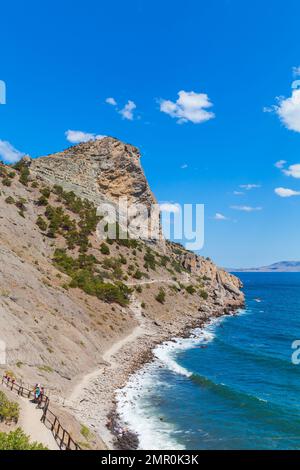 Novy Svit, Krim - 10. August 2020: Touristen laufen an einem sonnigen Tag auf dem Golitsyn Trail. Sommerlandschaft Krim. Novyi Svit, Gemeinde Sudak, Krim Stockfoto