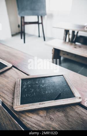 Eine altmodische Schiefertafel mit Schreibstift in einem Schulzimmer Stockfoto