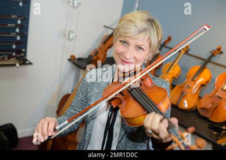 Reife Frau, die Geige spielt Stockfoto