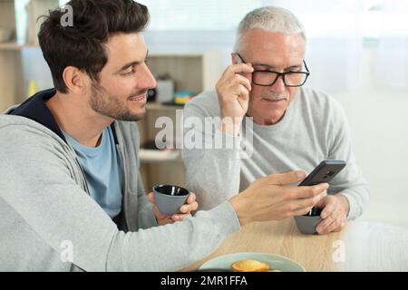 Vater und Sohn surfen auf dem Smartphone im Internet Stockfoto