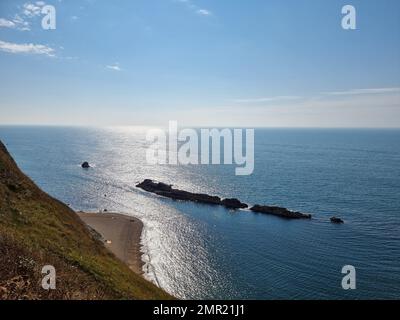 Durdle Door ist ein natürlicher Kalksteinbogen an der Jurassic Coast in der Nähe von Lulworth in Dorset. Der 120 Meter (390 Fuß) lange Isthmus, der den Kalkstein mit der Kreide verbindet, besteht aus einem 50 Meter (160 Fuß) langen Band aus Portlandkalkstein. Im Jahr 1811 nannte die erste Landkarte der Region die Region „Dirdale Door“. Durdle stammt aus dem alten englischen Durl, das heißt, durchbohren, bohren oder bohren, was wiederum von Thyrel abgeleitet wird, was Loch bedeutet. Der Teil des Namens Door behält wahrscheinlich seine moderne Bedeutung, die sich auf die Bogenform des Felsens bezieht; im späten 19. Jahrhundert wird er als „Ba“ bezeichnet Stockfoto