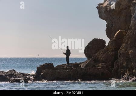 Ein Mann, der von den Felsen aus angeln will. Stockfoto