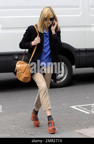Fearne Cotton chattet mit ihrem Handy und trägt Khaki-Hosen, eine schwarze Jacke und ein blaues Hemd in Kombination mit Sandalen mit Absatz und kurzen Knöchelstrümpfen, wenn sie die BBC verlässt. London, Großbritannien. 3/22/11. Stockfoto