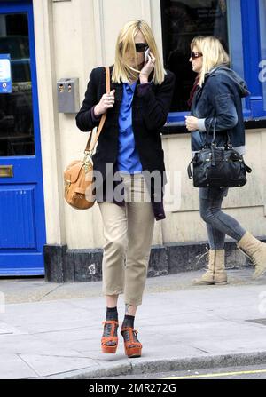 Fearne Cotton chattet mit ihrem Handy und trägt Khaki-Hosen, eine schwarze Jacke und ein blaues Hemd in Kombination mit Sandalen mit Absatz und kurzen Knöchelstrümpfen, wenn sie die BBC verlässt. London, Großbritannien. 3/22/11. Stockfoto