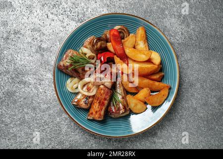 Köstliche gegrillte Rippchen und Garnierung auf grauem Tisch, Draufsicht Stockfoto