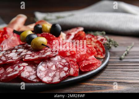 Leckere Salami und andere Delikatessen auf Holztisch, Nahaufnahme Stockfoto