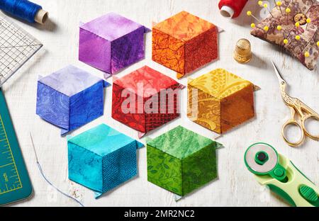 Diamanten in Form von Würfeln in den Farben Regenbogen, Steppdecken und Nähzubehör genäht. Stockfoto