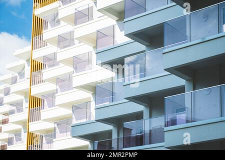 Fragment eines weißen, modernen Appartementhauses, Hotelgebäude mit Balkonen am blauen Himmel Stockfoto