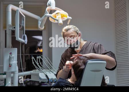 Kiew, Ukraine - 24. Dezember 2022: Zahnarzt, der mit einem Patienten in einer Zahnarztpraxis mit verschiedenen zahnärztlichen Instrumenten und Hilfsmitteln zur Behandlung zusammenarbeitet. Stockfoto