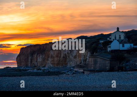 SEAFORD, ENGLAND - 22. JANUAR 2023: Blick auf die Coastguard Cottages auf den Klippen bei Sonnenuntergang im Winter, Cuckmere Haven, East Sussex Stockfoto