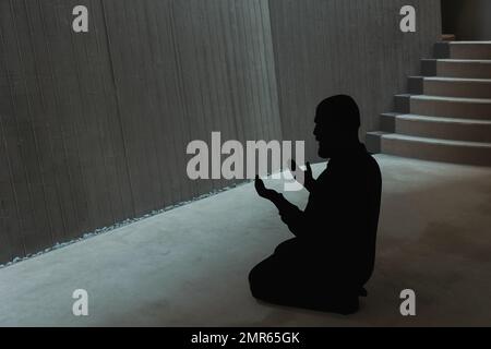 Silhouette eines muslimischen Mannes, der in der Moschee mit erhobenen Händen betet. Hintergrundbild aus Ramadan oder islamic. Istanbul Turkiye - 11.12.2022 Stockfoto