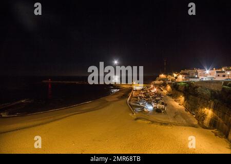 Monduntergang, Pier und Praia dos Pescadores von Largo das Ribas, dem historischen Zentrum des Dorfes Ericeira, an einem Winterabend in Portugal Stockfoto