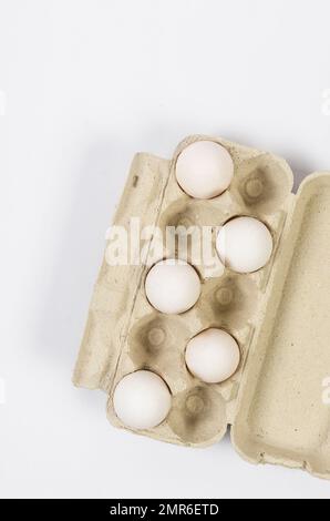 Frische weiße Hühnereier in einer Pappschale Nahaufnahme auf weißem Hintergrund. Gruppe mit fünf Eiern. Stockfoto