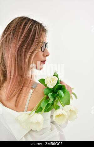 Rückansicht einer rothaarigen Frau mit einem Strauß weißer Tulpen. Stockfoto