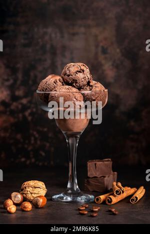 Lebensmittelfotografie von Schokoladeneis, Haselnuss, Walnuss, Zimt, Kaffee, Gefroren, kühl; Schaufel, Glas Stockfoto