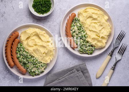 Lebensmittelfotografie mit Kartoffelpüree, Wurst, grünen Erbsen, Schnittlauch, Abendessen, Mittagessen, Brunch, Frühstück Stockfoto