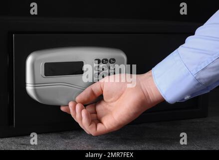 Mann öffnet schwarzen Stahlsafe mit elektronischem Schloss, Schließung Stockfoto