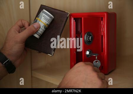 Ein Mann, der Pass und Geld in einen kleinen Stahlsafe steckt Stockfoto