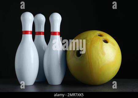 Gelbe Bowlingkugel und Nadeln auf einem Tisch aus schwarzem Stein Stockfoto