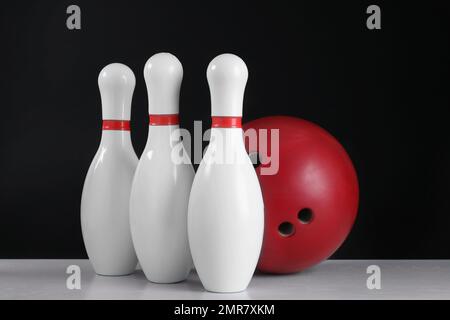 Rote Bowlingkugel und Stifte auf grauem Tisch Stockfoto