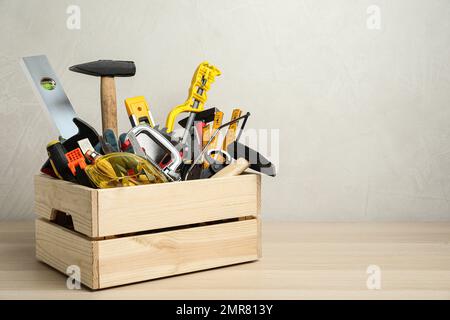 Kiste mit verschiedenen Zimmermannswerkzeugen auf Holztisch. Platz für Text Stockfoto