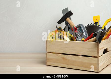 Kiste mit verschiedenen Zimmermannswerkzeugen auf Holztisch. Platz für Text Stockfoto