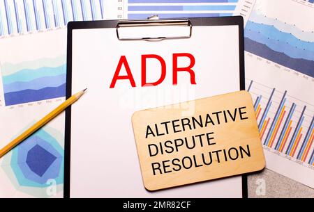 AdR Alternative Dispute Resolution ist in einem weißen Notizblock neben einem Taschenrechner, Kaffee, Gläsern und einem Stift geschrieben. Geschäftskonzept Stockfoto