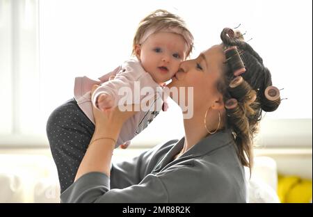 Mutter mit Lockenwicklern im Haar, kuschelnd mit Tochter, Baby, Kleinkind, Mädchen, 5 Monate, Baden-Württemberg, Deutschland, Europa Stockfoto