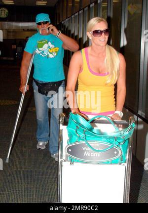 Exklusiv!! Terry Bollea (alias Hulk Hogan) und Freundin Jennifer McDaniel kommen nach einem Flug von Tampa am Miami International Airport an. Die beiden spazierten langsam durch das Terminal, während Hulk vorsichtig ging und Krücken benutzte, weil er vor kurzem eine Rückenoperation durchgeführt hatte. Jennifer schiebte ihren Gepäckwagen und half ihm, auf dem Boden einer Rolltreppe zu navigieren, bevor die beiden den Fahrer ihres wartenden Wagens trafen, der sich um ihr Gepäck kümmerte. Hogan war gestern in einem hitzigen Gerichtsstreit in Tampa mit der Anwältin der Ex-Frau Linda Bollea verwickelt, nach einer Anhörung, in der Hulk einen Richter bat, ihm Zugang zu gewähren Stockfoto