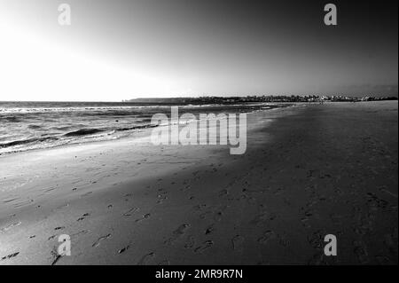 Ein verlassener Sandstrand und eine City Skyline in der Ferne Stockfoto