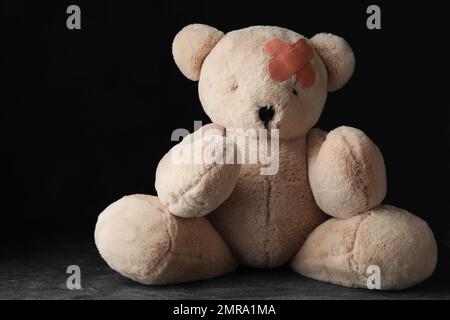 Spielzeugbär mit Pflastern auf dem grauen Steintisch Stockfoto