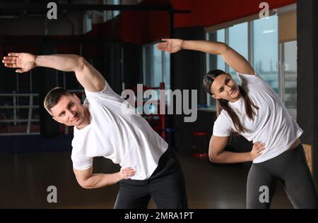 Ein Paar, das sich nach dem Training in einem modernen Fitnessstudio dehnt Stockfoto